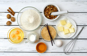 Breakfast Cheesecake Baking cake in rural kitchen - recipe ingredients (eggs, flour, milk, butter, sugar, walnuts, spices) on white wooden table from above.