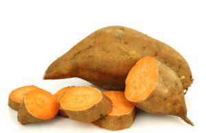 Seasonal Produce Boosts Performance one whole sweet potato and a cut one on a white background