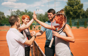 Look For New Sparring Partners Four young friends giving a high-five after tennis training. Selective focus.