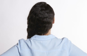 The Spine Is Everything Photo of woman taken from behind while she holds her hands at her side as if she is experiencing back pain.