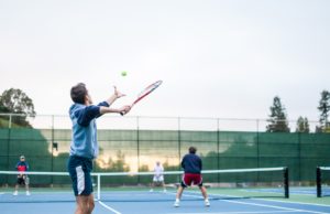 Keys To Holding Serve man serving in a tennis doubles match