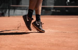 Achilles Tendonitis Close-up of a tennis player's feet as he is serving on a clay court.