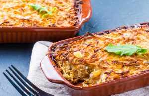 Quick Breakfast Casserole Close up view of appetizing potato casserole with fish, eggs and cream. Potato casserole in serving baking dish on dark concrete background