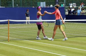 Taking The High Road Two female tennis players shaking hands at the net.