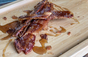 Sweet & Spicy Candied Bacon candied bacon with salt served on a wooden serving tray