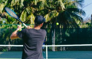 Adding Racquet Head Speed To Your Shots Man practicing his groundstrokes on a tennis court.