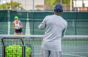 What To Look For In Hiring A Tennis Professional/Coach Tennis coach and female student on court.