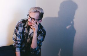 Good Question Nov/Dec 2023 Young man in glasses with hand to face, pondering.