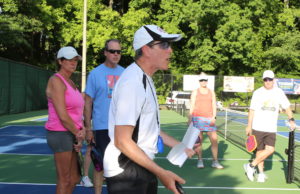 Safeguard Your Eyesight Pickleball instructor on outdoor court surrounded by players learning the game.
