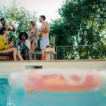 Friends enjoying drinks by the poolside during summer vacation