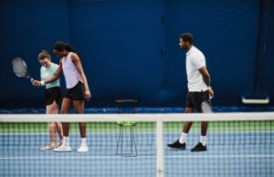 Four Easy Tips to Improve Your Practice and Match Play Performance Full length portrait of female tennis coach working with young African American woman during practice at indoor court