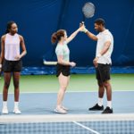 Young Woman Teaching Friends Play Tennis