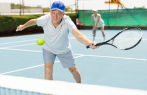 The Secret to Playing Better Tennis at Any Age Portrait of concentrated elderly man playing tennis with friend on court.