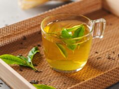Warm Up In Cold Weather With Liquid Sport Nutrition Green tea brewed in cup with tea leaves on table. Closeup.