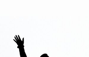 Good Question: January/February 2026 silhouette of woman standing in a crowd with hand raised as if she is asking a question.