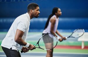 2 Up Wall Side view portrait of two young African American people playing tennis at indoor court, copy space