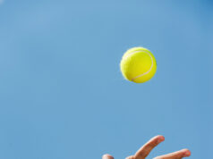 The Flight Of The Ball And What You Have To Say About It! Serving ball. Close-up of male hand in wristband throwing tennis ball against blue sky
