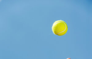 The Flight Of The Ball And What You Have To Say About It! Serving ball. Close-up of male hand in wristband throwing tennis ball against blue sky
