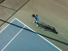 Six Keys To Improving Your Tennis Game Aerial view of African American woman at the tennis court service line.