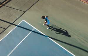 Six Keys To Improving Your Tennis Game Aerial view of African American woman at the tennis court service line.