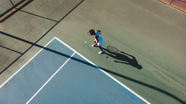Aerial view of African American woman at the tennis court service line.