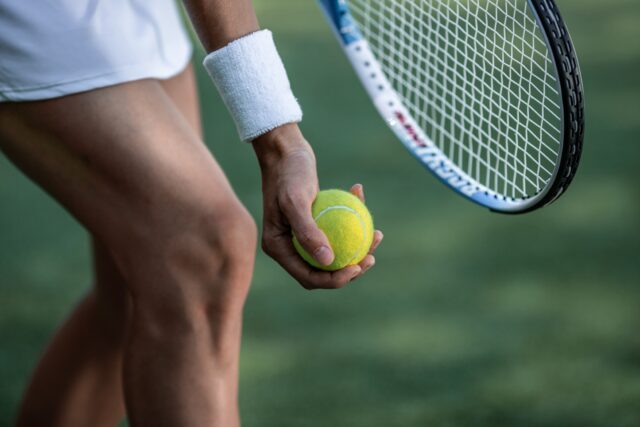 Tennis player in sportswear with a ball close-up