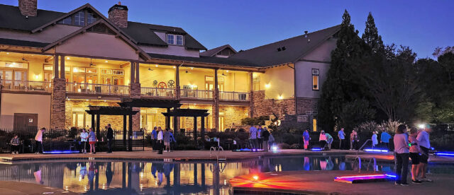 The back of the Soleil Clubhouse is lit up as residents enjoy a special evening of glow-in-the-dark putt-putt golf around the outdoor pool.