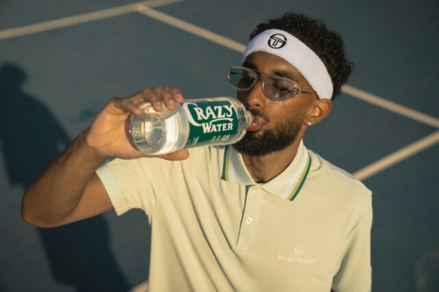Tennis player on court drinking from a bottle of water.