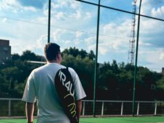 Take Back The Court Male tennis player standing on a court with a racquet bag over his shoulder.