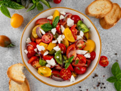 Tomato, Peach, and Burrata Salad A salad of farm fresh multi-colored tomatoes, red onion, fresh basil and feta cheese in a bowl. Summer salad. Top view