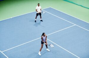 Doubles Communication Minimal high angle shot of African American couple playing tennis in pair at indoor court, copy space