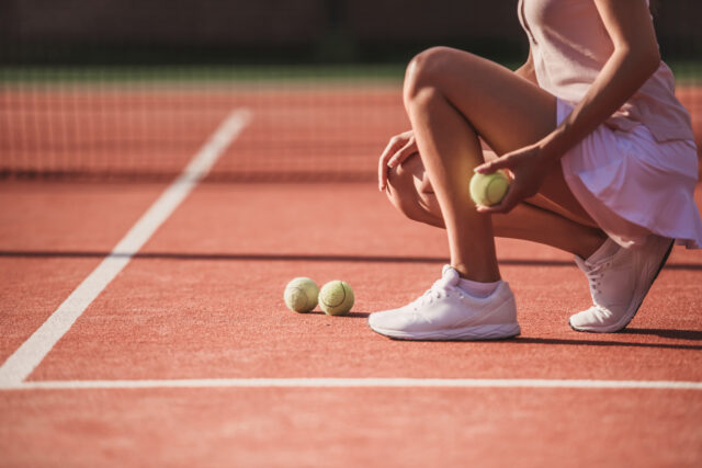 Girl playing tennis Cropped image of girl holding a tennis ball while playing tennis on court outdoors